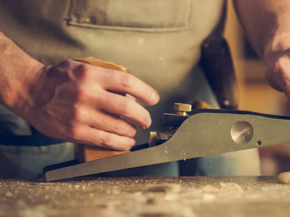 Tischler beim Hobeln einer Eichenbohle in der Werkstatt